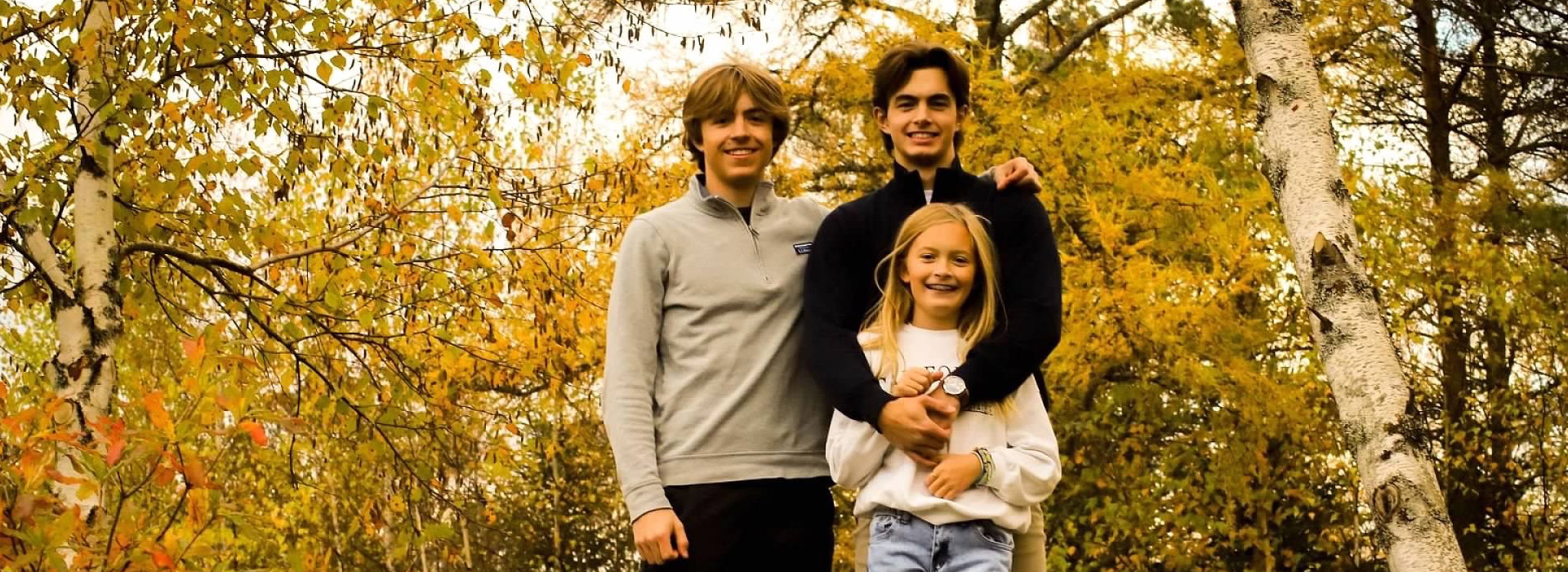 Norfolk siblings standing together in a fall forest scene
