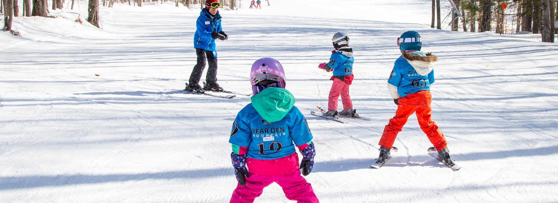 Three young children on skis learning from an instructor outside the Bear Den at Whiteface Mountain