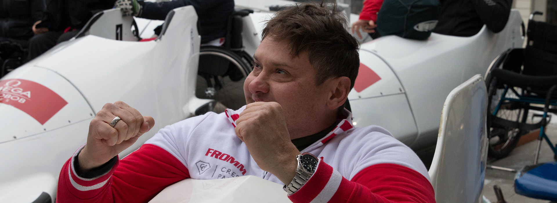 A para bobsled athlete in his sled with fists in the air in celebration of his run.