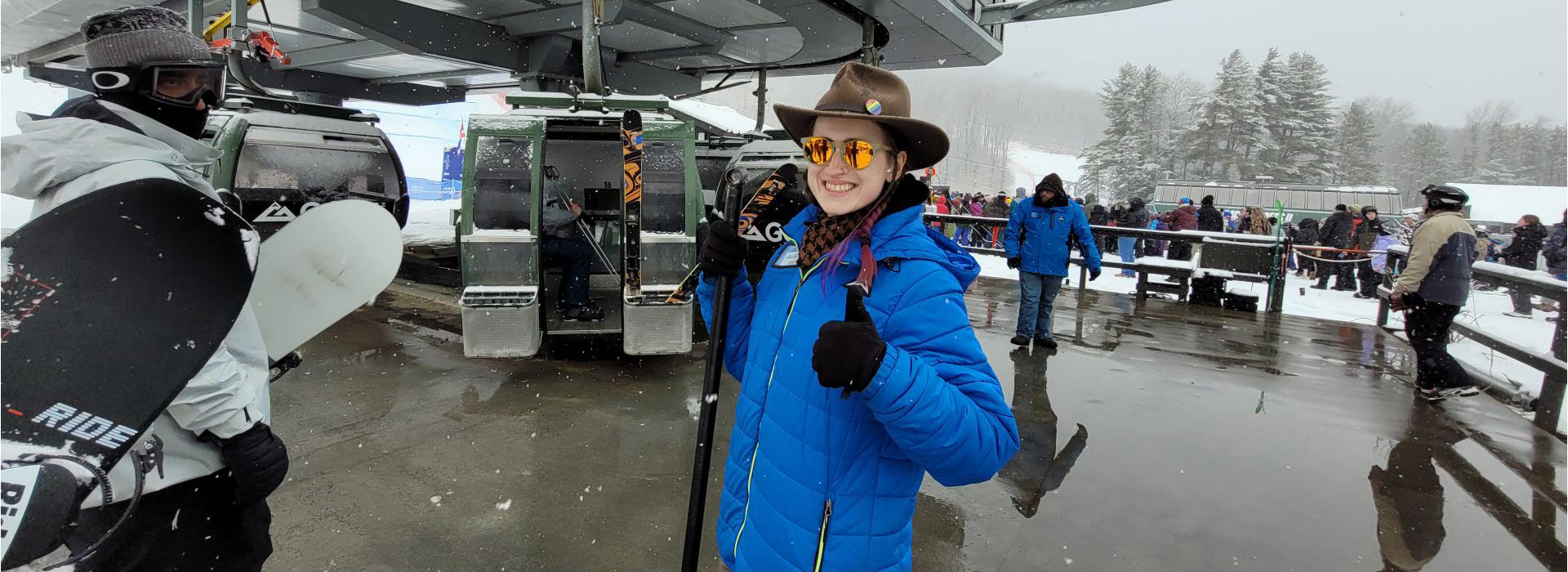 A Gore Mountain staff member helping load the gondola and giving a big thumbs up with a smile during the FISU Games.