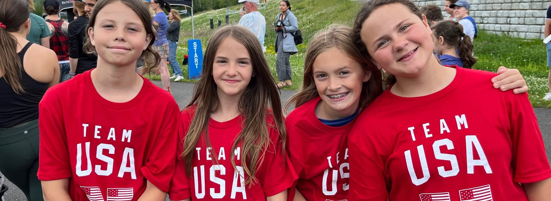 Four young girls in red Team USA t-shirts together getting ready to participate in an Olympic Day run at Mt Van Hoevenberg.