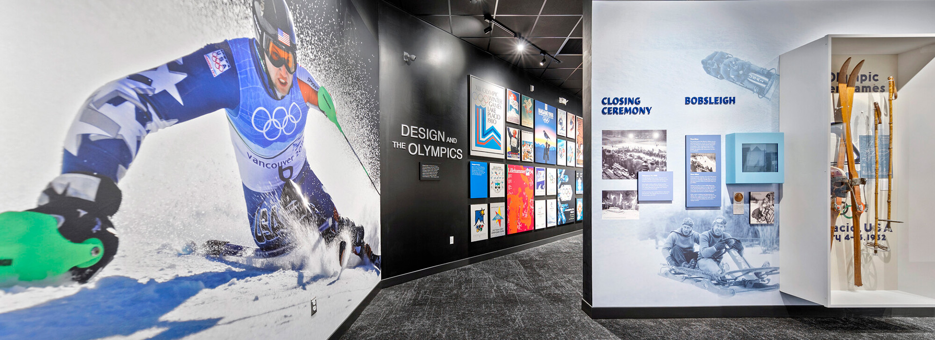 Image of the inside of the Lake Placid Olympic Museum showing a larger than life portrait of skier Andrew Weibrecht on the left and other exhibits.