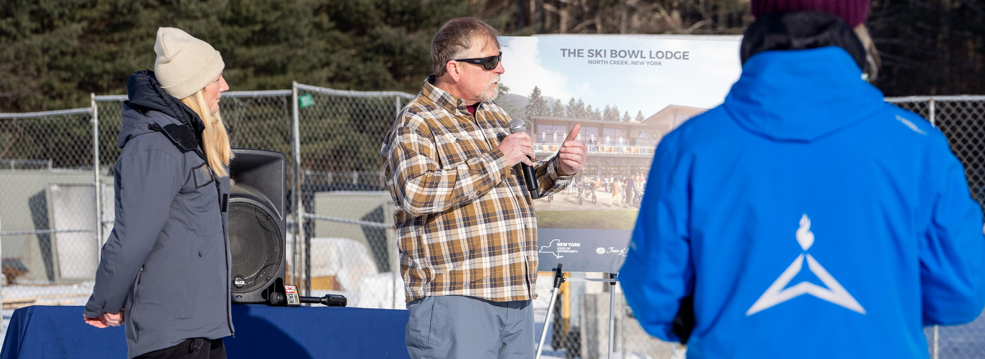 Gore general manager James Bayse speaks outside on a bright winter day with Olympic Authority President and CEO Ashley Walden standing by.