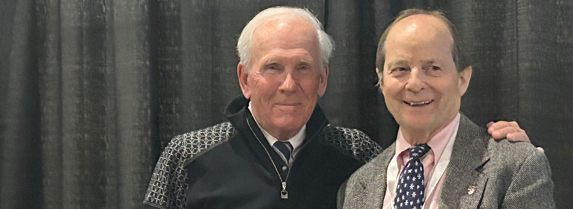 Jeff Byrne stands on stage with the International Skiing History Association presenter of the awards.