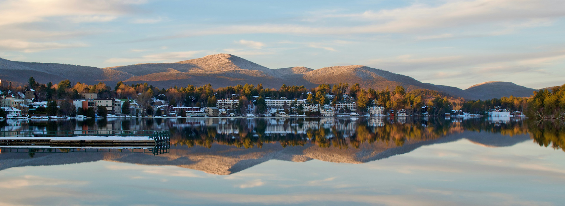 Downtown Lake Placid on a winters day as seen from across Mirror Lake before the lake is frozen with a beautiful reflection of the entire scene.