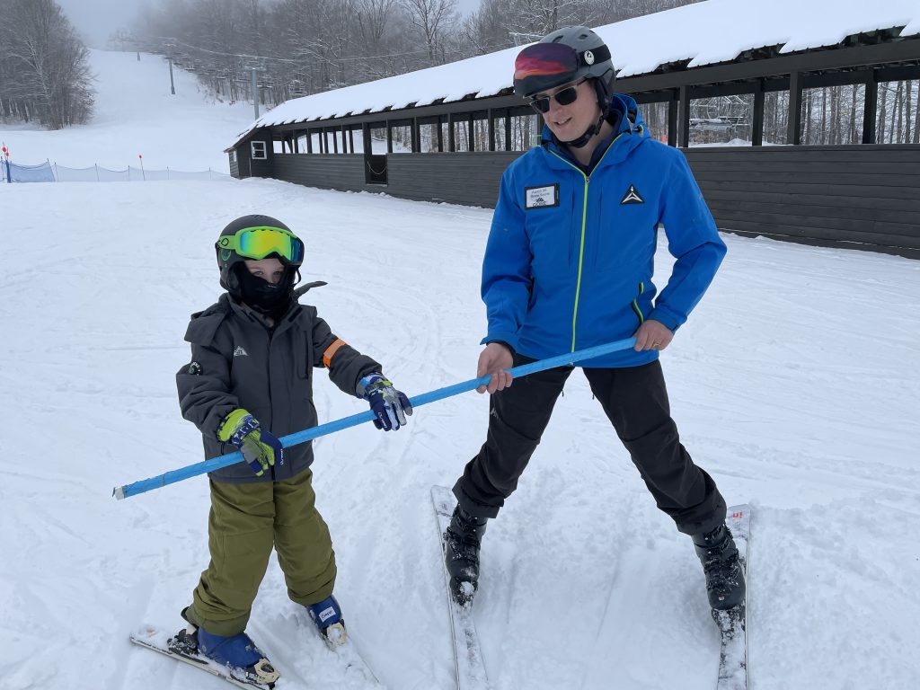 A Gore Mountain ski instructor at the left helping a Johnsburg elementary school student learn to ski.