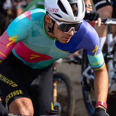 Christopher Blevins riding in a crowd of riders in the 2024 WHOOP UCI Mountain Bike World Series at Mt Van Hoevenberg.