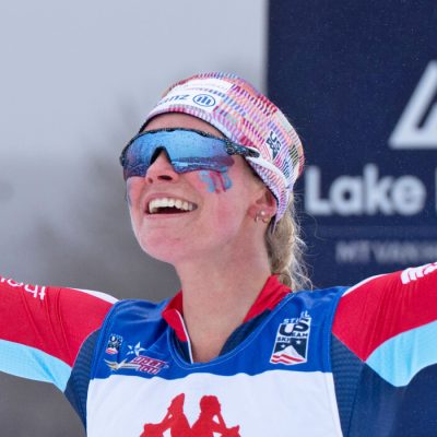A close up of Jessie Diggins at Mt Van Hoevenberg, smiling with her arms outstretched after completing a race.