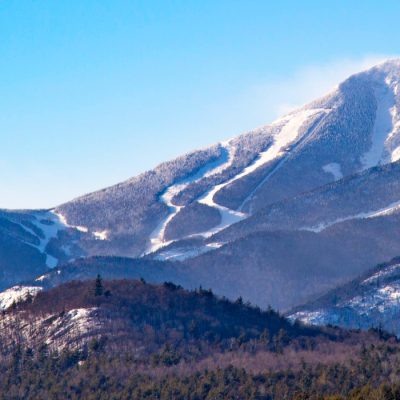 Whiteface Mountain from a distance, showing it's white ski trails in winter against a pure blue sky.