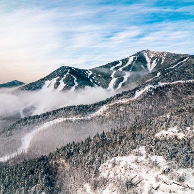 Whiteface Mountain ski area in winter from a distance with a partially cloudy sky and light fog at the lower elevations